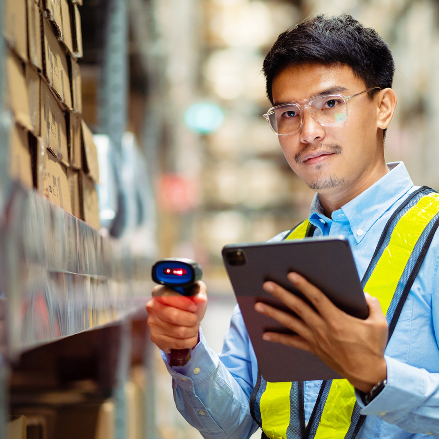 A person wearing a high-visibility jacket scanning a box in a warehouse