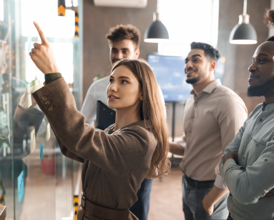 woman pointing to graphs on board with work colleagues